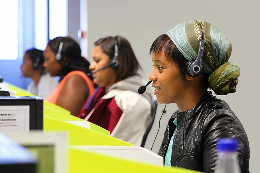 Lifeline South Africa call centre counsellor wearing a headset, with colleagues working alongside her